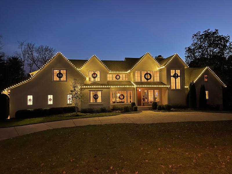 Large home at dusk with lights and wreaths in every window