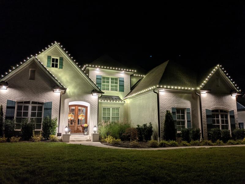 Brick and stucco home with lights on every gable