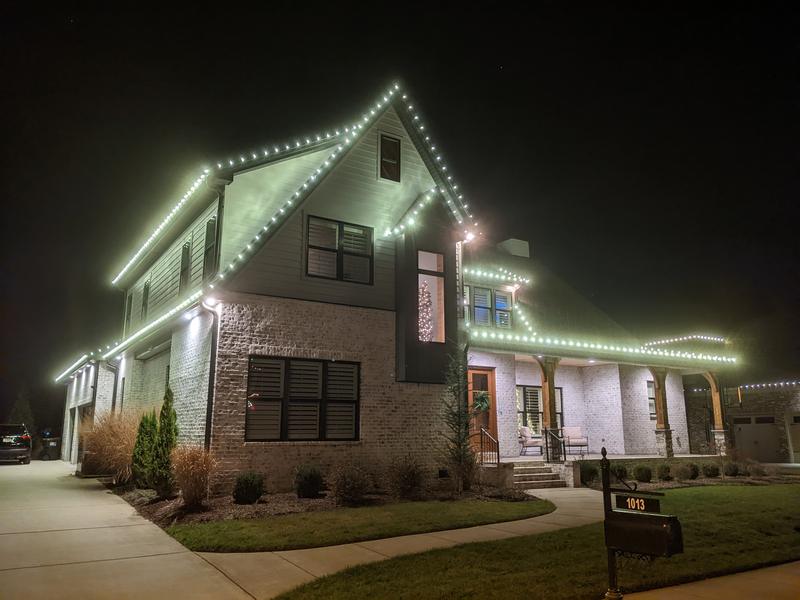 Corner home with a tall lit gable and wraparound porch