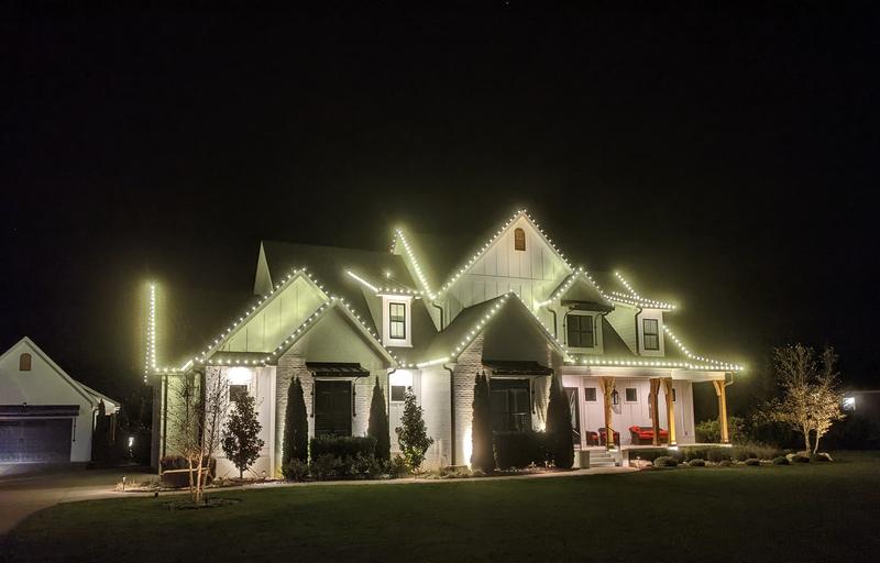 Home with lit rooflines and a detached garage