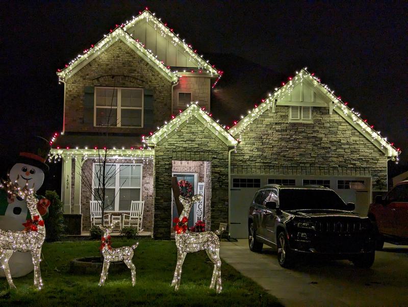 Stone home with red accent lights, reindeer and a snowman