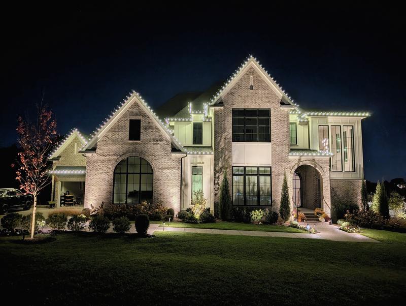 Two-story brick home lit along every peak