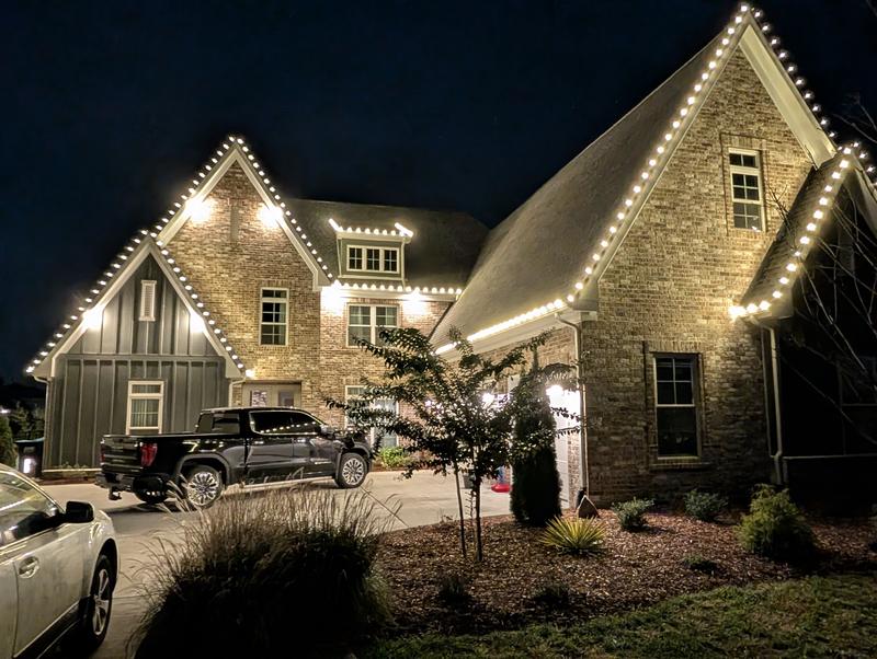 Stone home with steep gables outlined in white lights