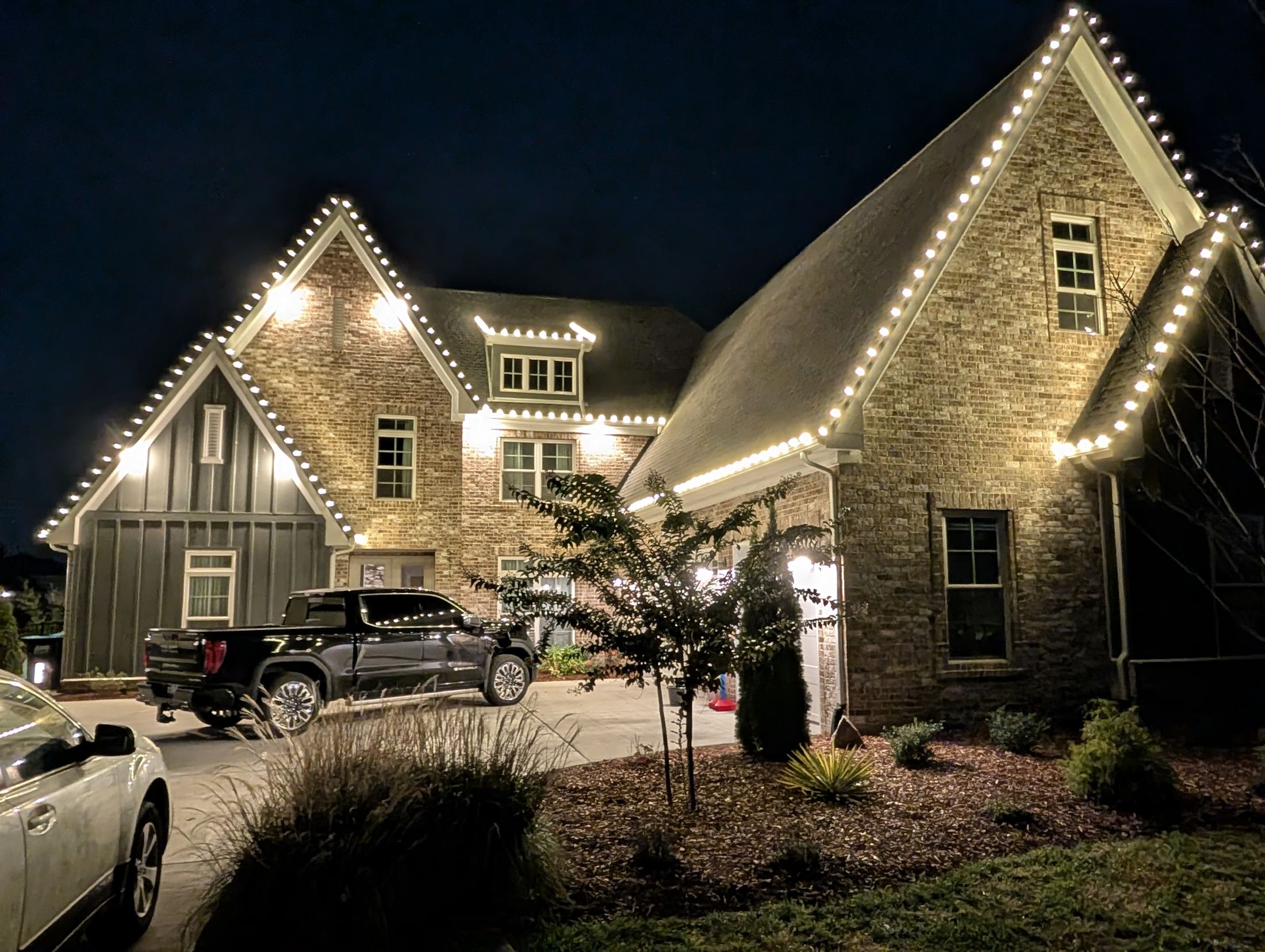 Stone and board-and-batten home outlined in white lights