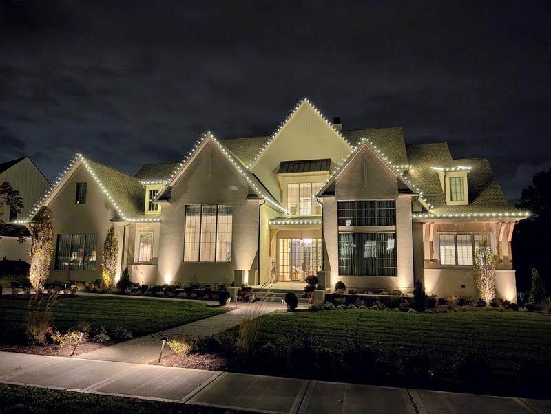 Wide estate home outlined in warm white lights