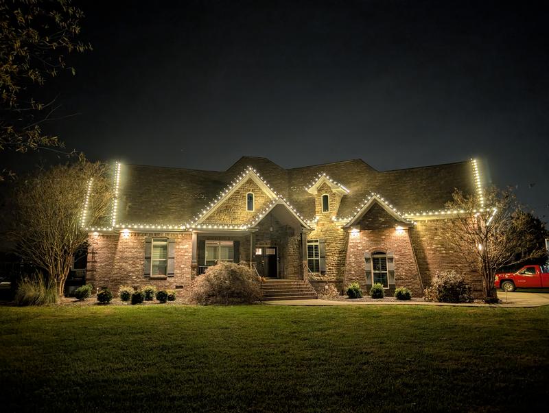 Brick home with lights across a wide roofline