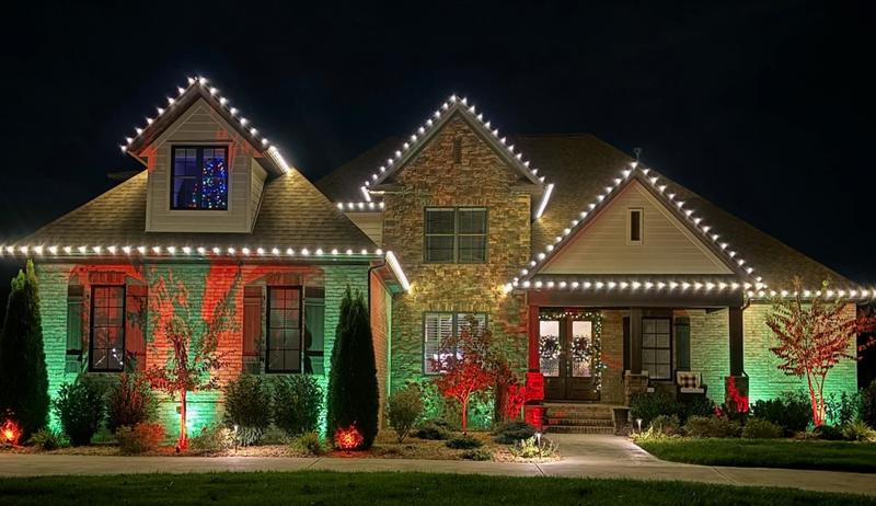 Home with white roofline lights and green and red uplighting