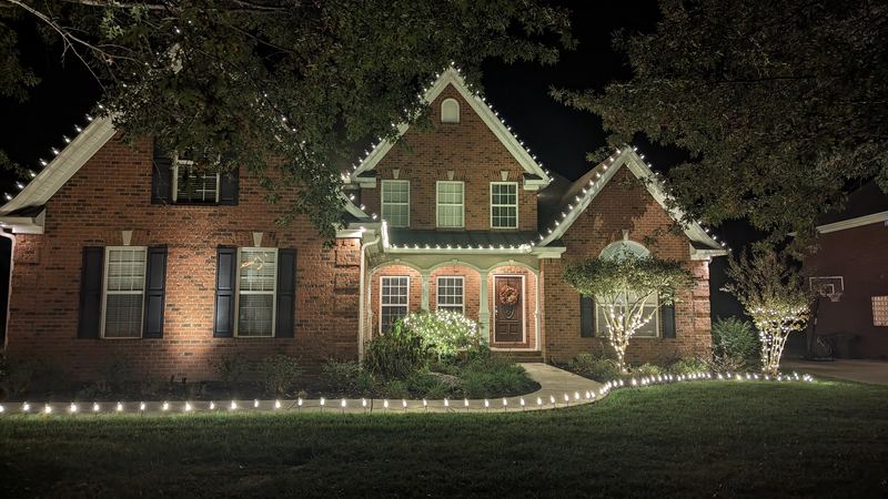 Brick home with white roofline lights and a lit walkway