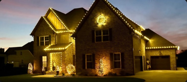 Brick home with warm white lights on every roofline at dusk